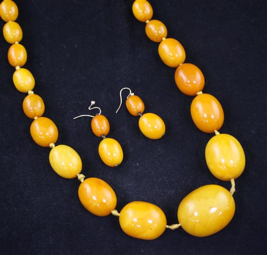 A single strand graduated oval amber bead necklace and pair of double bead earrings, 39in.